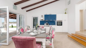 A dining area with a table set for four, a kitchen with blue cabinets, and a staircase leading to an upper level.