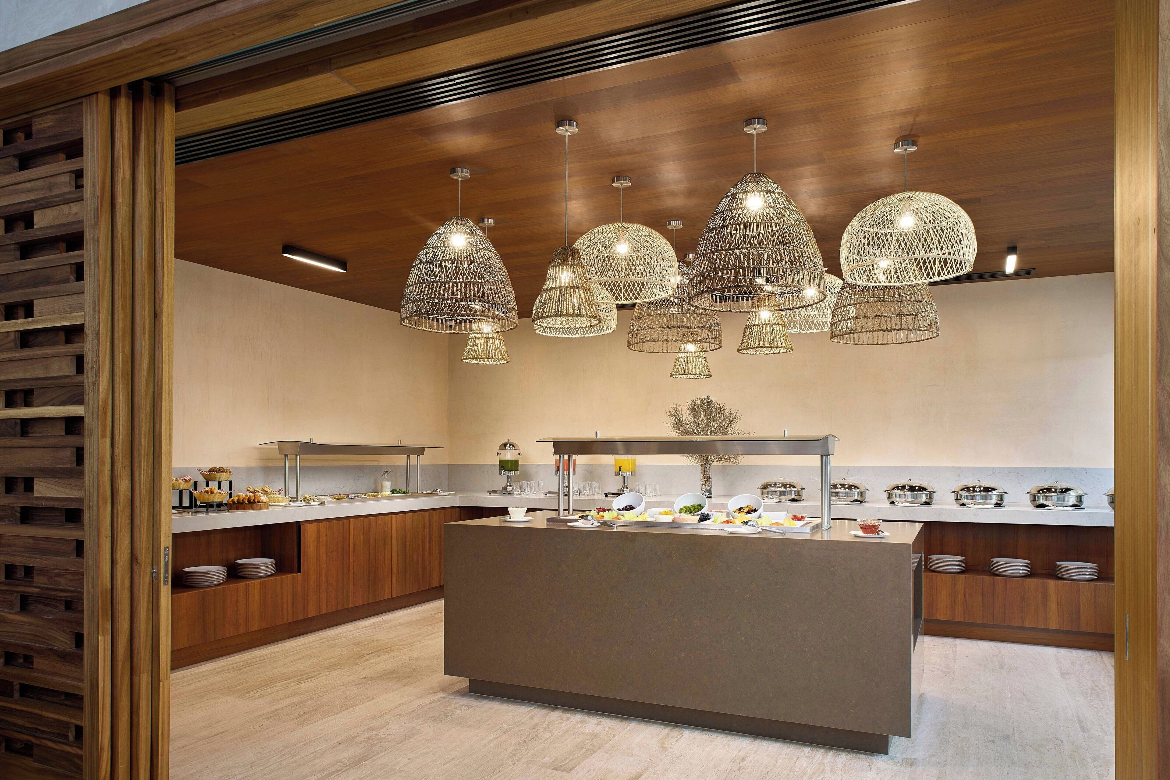 Uma cozinha moderna com ilha central, luminárias pendentes e armários de madeira.