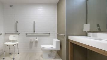Un baño moderno con azulejos blancos tipo metro, inodoro blanco, lavabo blanco y un espejo.