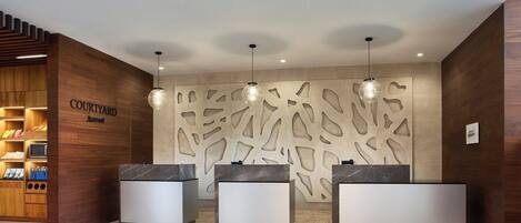 A modern reception area with three reception desks, a wooden wall with a unique pattern, and pendant lighting.