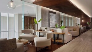 Eine moderne Hotelhalle mit einer langen Rezeption, einer Sitzgelegenheit und großen Fenstern.