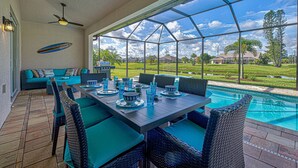 An outdoor patio with a pool, wicker furniture, and a view of the surrounding landscape. - Pelican Shores | 2 King Suites | Pool | Jacuzzi | Lounge (Rotonda West)