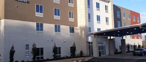 A Holiday Inn Express & Suites hotel with a modern design, featuring multiple floors and a covered parking area.