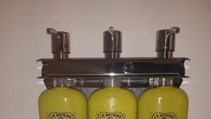 Three J.R. Watkins products: shampoo, conditioner, and shower gel, all in yellow bottles with silver pumps. - Holiday Inn Express & Suites Jackson by IHG (Jackson)