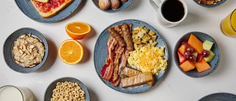 A breakfast spread with various dishes including toast, fruit, cereal, and eggs.