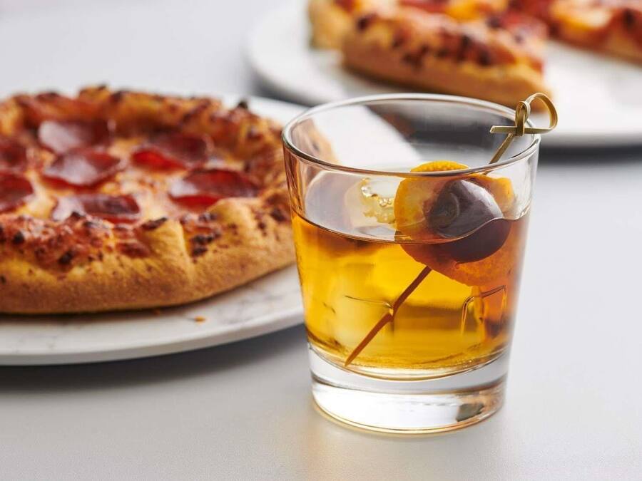 Una pizza con pepperoni y una cerveza con aceituna.