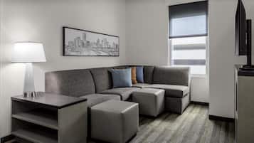 Uma sala de estar moderna com um sofá seccional, uma mesinha lateral e uma obra de arte com vista para a cidade na parede.