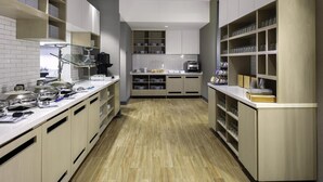 Een moderne keuken met witte kastjes, houten planken en een betegelde spatwand.
