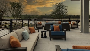 Een terras op het dak met buitenmeubels, waaronder een bank en stoelen, en uitzicht op het omliggende landschap.