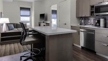 Cozinha moderna com ilha central, eletrodomésticos de aço inoxidável e televisão de tela plana.