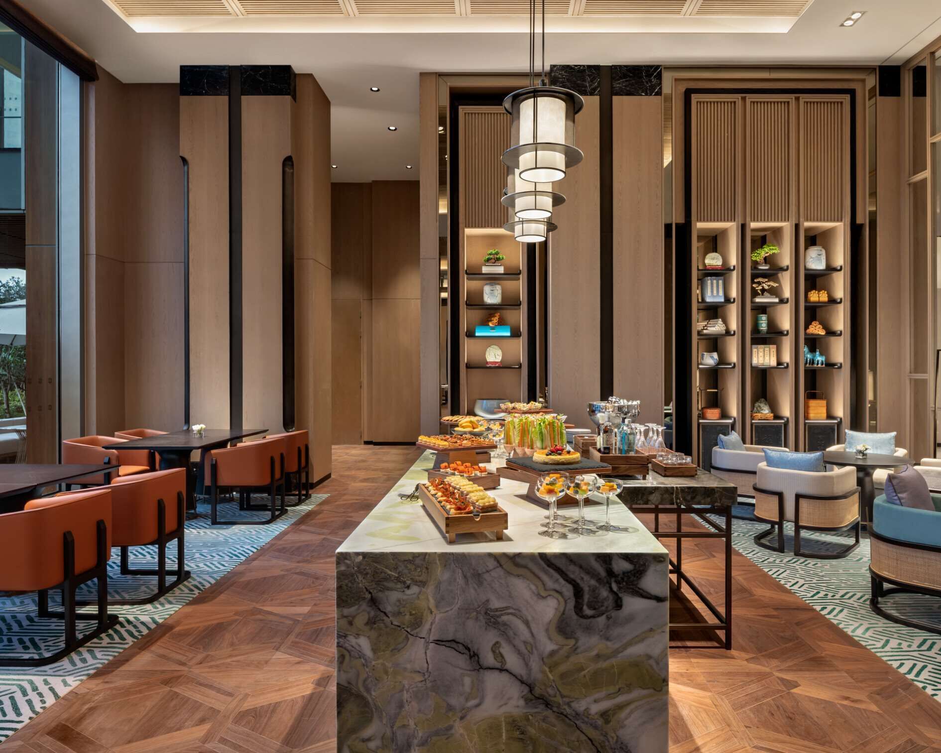 A modern hotel lobby with a marble reception desk, seating area, and decorative shelves.