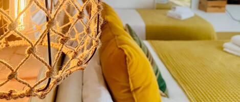 Una cama con ropa de cama blanca y amarilla, una manta verde y una almohada amarilla.