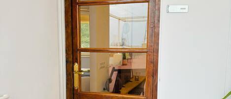 A wooden door with a glass panel, a small step leading to the entrance, and a red chair to the left.