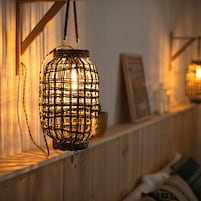 Un farol de mimbre colgado de una viga de madera, con un estante debajo.
