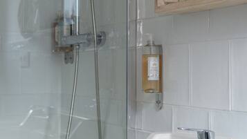 A bathroom with a shower, a sink, and a wooden medicine cabinet above the mirror.