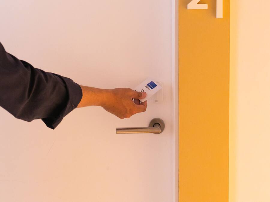 Una mano insertando una llave en la cerradura de una puerta.