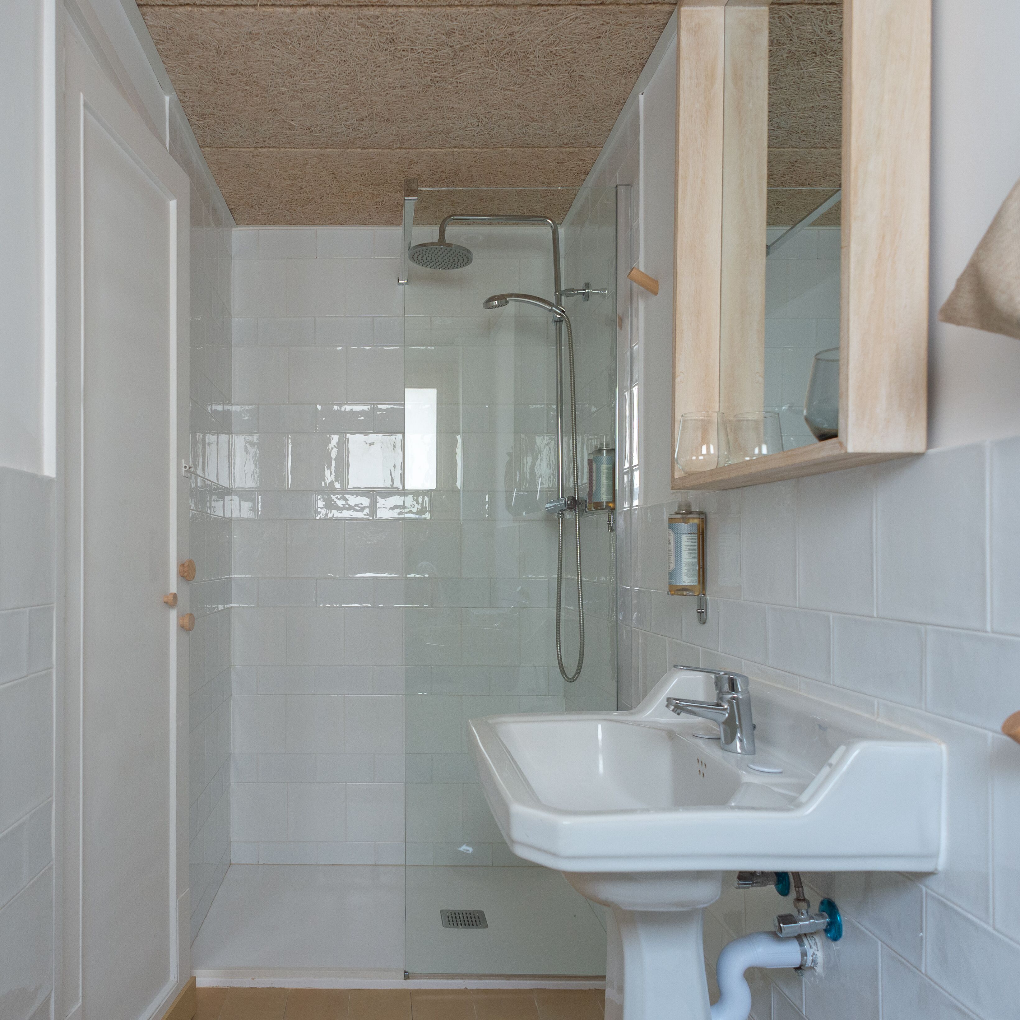 A bathroom with a glass-enclosed shower, a white sink, and a wooden-framed mirror.