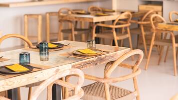 A restaurant interior with wooden tables and chairs, a counter with a menu, and a wall with various items pinned.