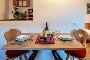 Una mesa de comedor servida con platos, vasos y un jarrón con flores.