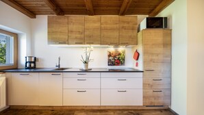 A kitchen with wooden cabinets, a microwave on top, a sink, and a potted plant. - Apartment “Ritten Gfliererhof” with Mountain View, Garden & Balcony (Völs am Schlern)