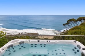 A hot tub with a view of the ocean and beach.