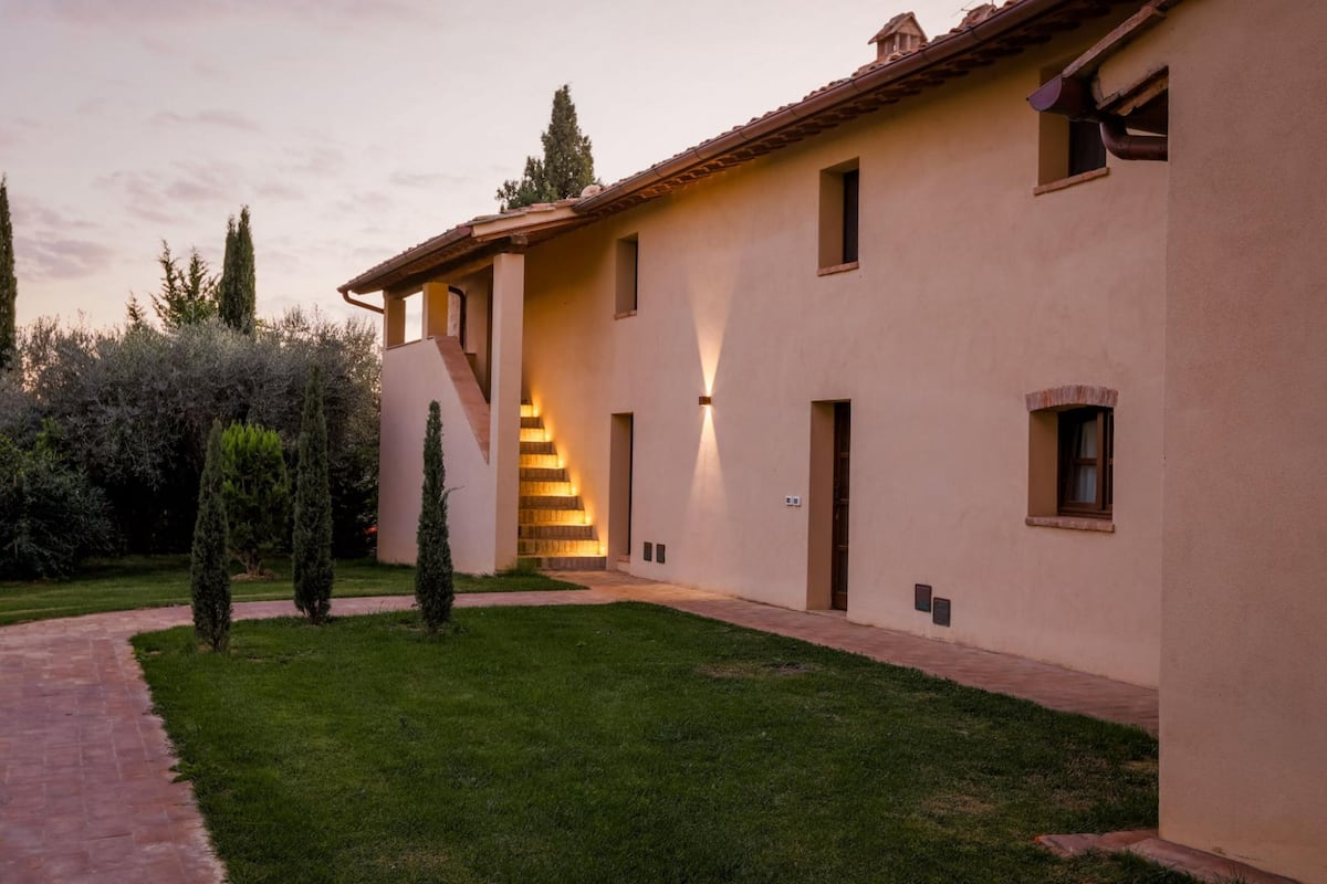 A modern building with a light-colored exterior, a central staircase, and a well-maintained lawn.