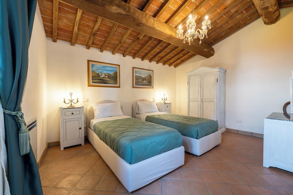 A bedroom with two beds, a wardrobe, and a chandelier.