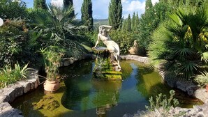 A garden with a pond, statues, and tall trees. - Tenuta Tegolato (Barberino Tavarnelle)