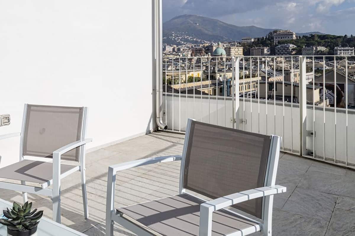 A balcony with two white chairs and a small table with a plant.