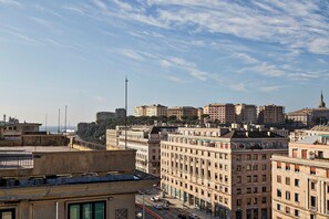 A cityscape with multiple high-rise buildings, a prominent street with cars, and a clear sky. - Deluxe Apartments by Wonderful Italy (Genoa)