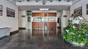 A lobby with a polished granite floor, wooden paneling, and a large potted plant. - Deluxe Apartments by Wonderful Italy (Genoa)