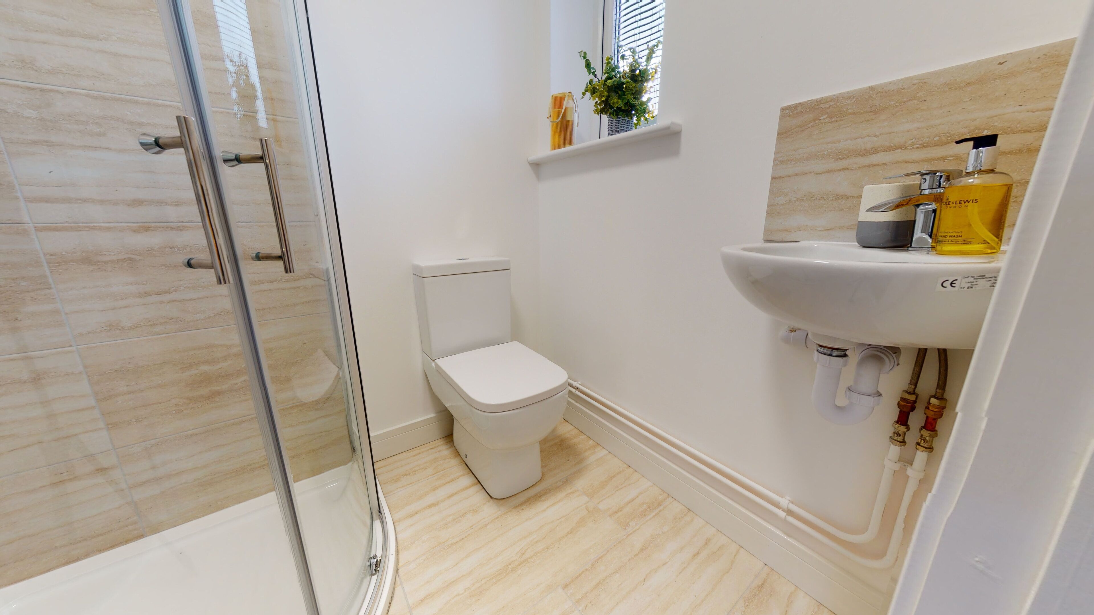 A modern bathroom with a glass shower enclosure, a white toilet, and a sink with toiletries.