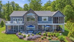 A two-story house with a stone facade, large windows, and a covered patio area. - Great Dock! Wifi, Propane Fire-Pit!  Come Visit "Dock Holiday"! (Huddleston)