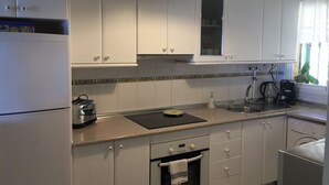 Une cuisine avec des meubles blancs, une cuisinière, un évier et une machine à café.