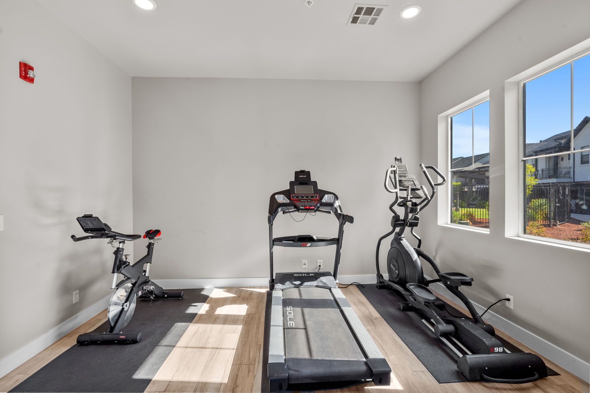 Un gimnasio con cintas de correr, elíptica y bicicleta estática.