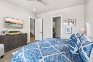 A bedroom with a bed, dresser, TV, and framed pictures.