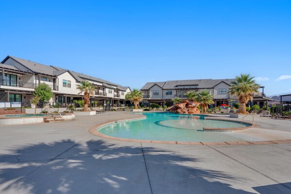 A residential area with a swimming pool surrounded by houses, palm trees, and a clear sky. - Sunsplash Retreat at Ocotillo Springs, Sleeps 16 New Beautiful Home, near Resort Amenities (Santa Clara)