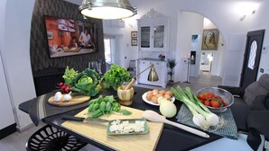 Uma cozinha com diversos vegetais frescos, uma tábua de corte e uma faca sobre o balcão.