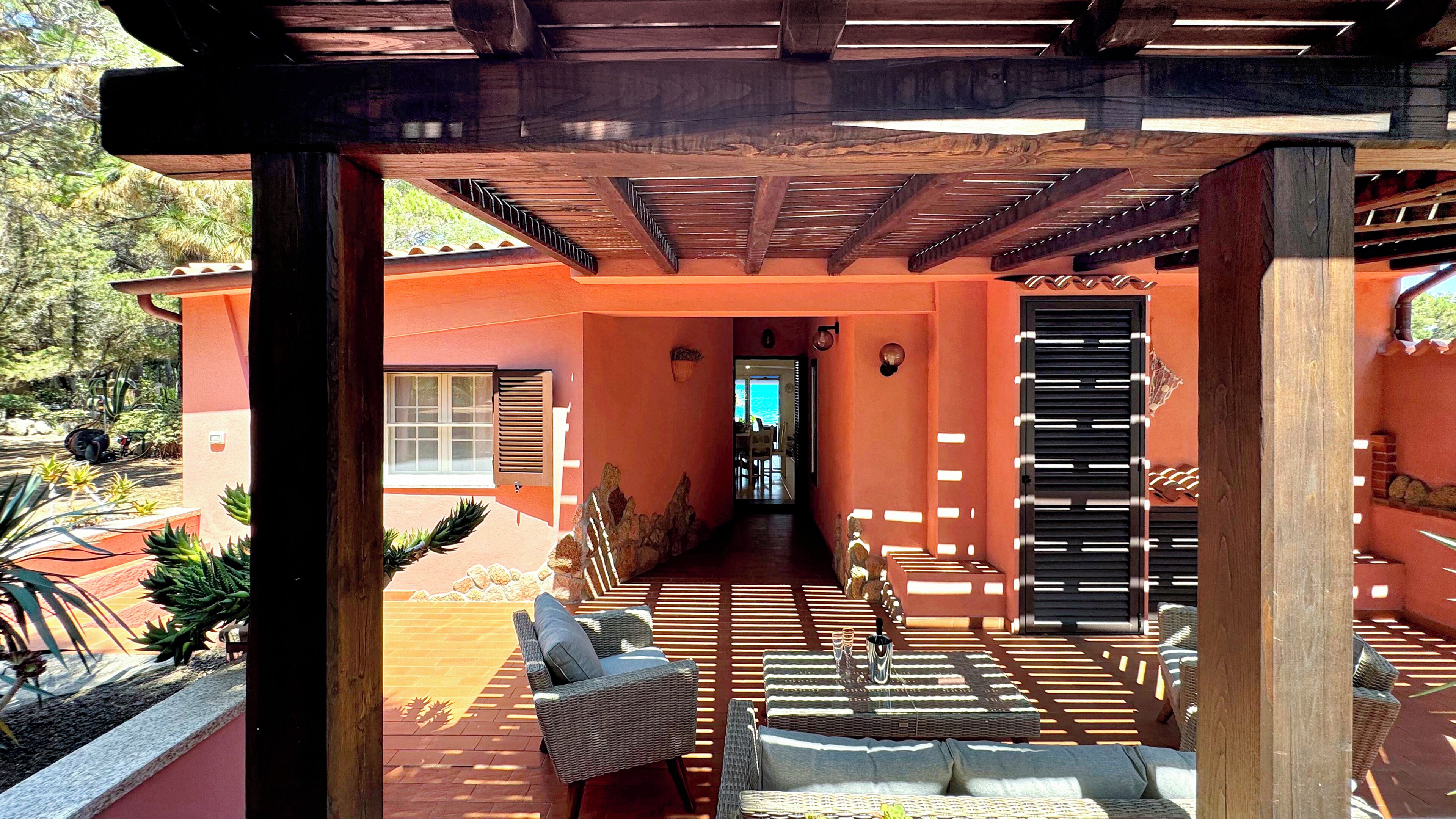 An outdoor patio area with a pergola, seating, and a view of the ocean.