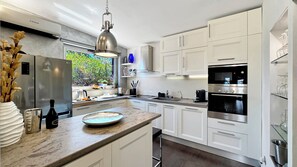 Una cocina moderna con armarios blancos, electrodomésticos de acero inoxidable y encimera de mármol.