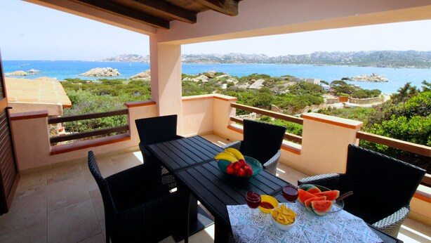 A balcony with a table set for two, featuring a view of the sea and mountains. - Villa Iole (La Maddalena)