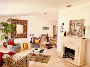 Cozy seating area with a fireplace, comfortable armchair, and a stylish mirror.
