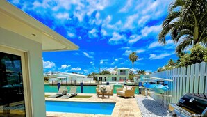Un espace piscine doté d’une terrasse carrelée, d’un barbecue et offrant une vue sur un quartier résidentiel.