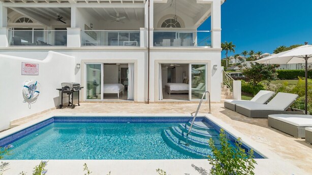 A two-story building with a swimming pool and outdoor seating.