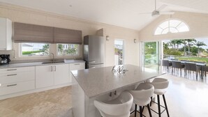 A modern kitchen with a large island, bar stools, and a view of the outdoors.