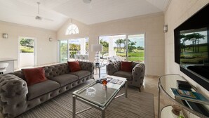 A spacious living room with a large sectional sofa, a glass coffee table, and a flat-screen TV.
