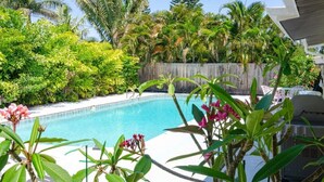 Una piscina rodeada de exuberante vegetación y una valla de madera.