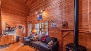 A cozy cabin interior with a wooden interior, a fireplace, a sofa, and a kitchen area. - Rainbow Trout Cabin quick drive to fishing lakes, backs forest, kitchen heat+AC (Payson)