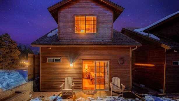 A wooden cabin with a large window and a sliding glass door, two chairs outside, and a starry night sky. - Rainbow Trout Cabin quick drive to fishing lakes, backs forest, kitchen heat+AC (Payson)