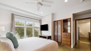 Quarto com cama, televisão, guarda-roupa e ventoinha no teto.